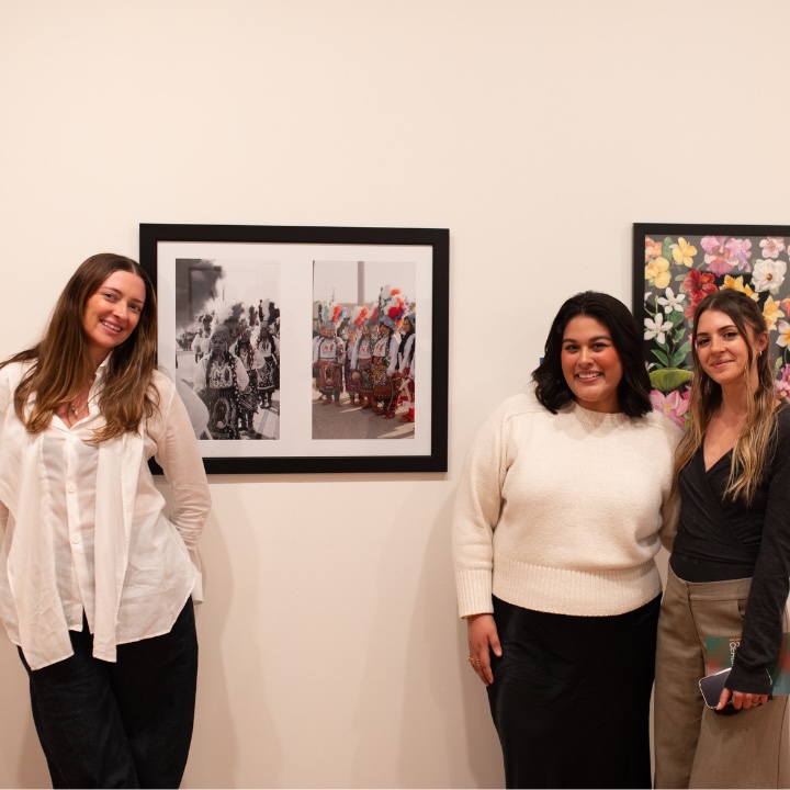 three students stand by a wall of art